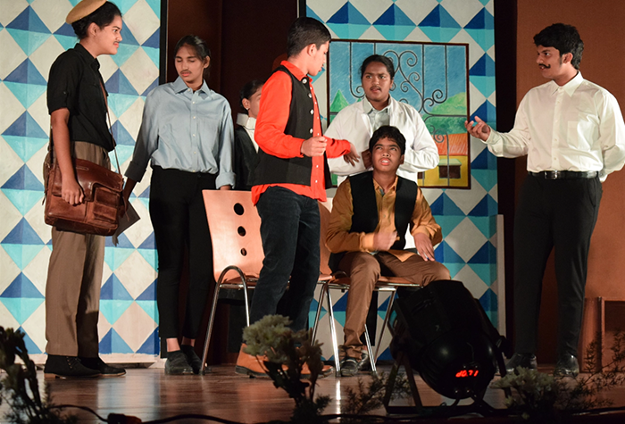 Students on a stage enacting a play, dressed in theatrical costumes.