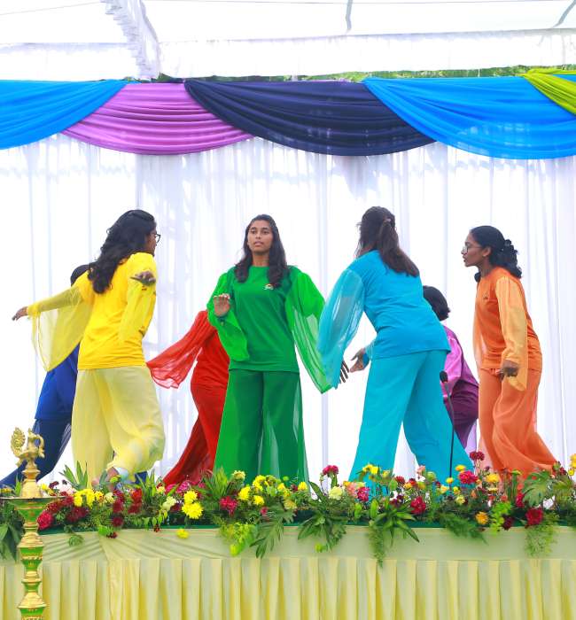 A group of students move in a circle on stage in a Eurythmy performance.