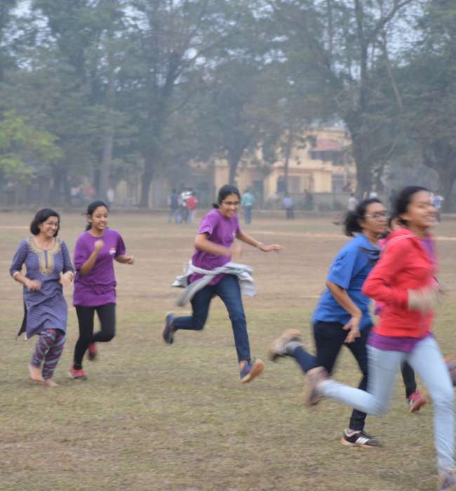 High school students running on a ground during an athletic activity.