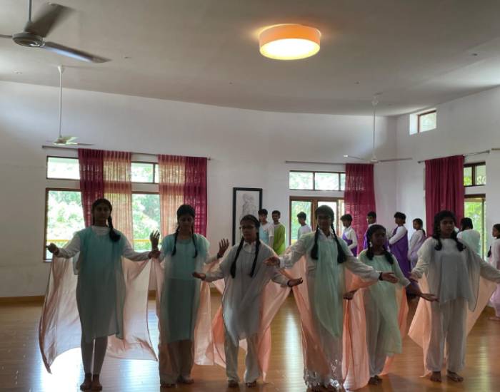 Sloka students dressed in flowy garments move synchronised in a Eurythmy performance.