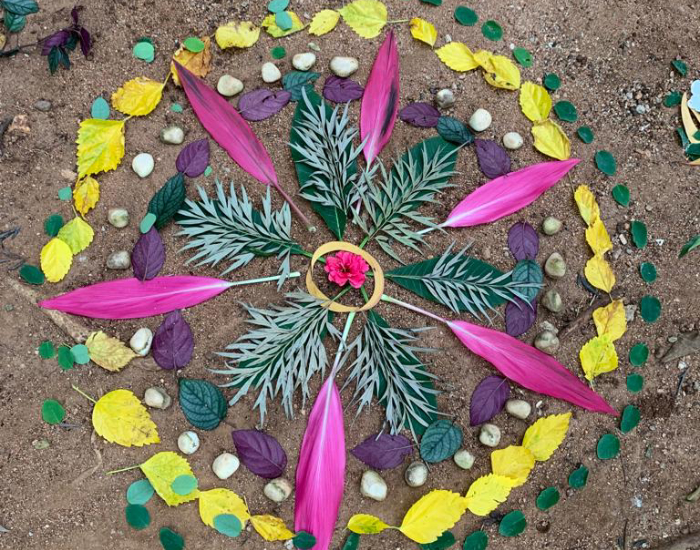 A mandala on the ground, made of flowers and leaves