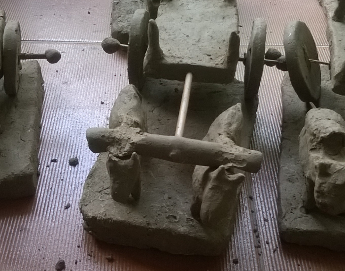 Clay sculptures of bullock carts left to dry on a surface