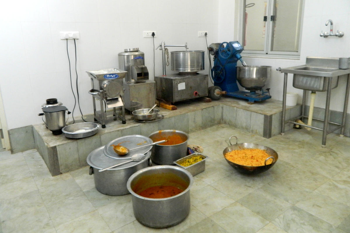 Inside view of the kitchen; utensils filled with cooked food rest on the kitchen floor.