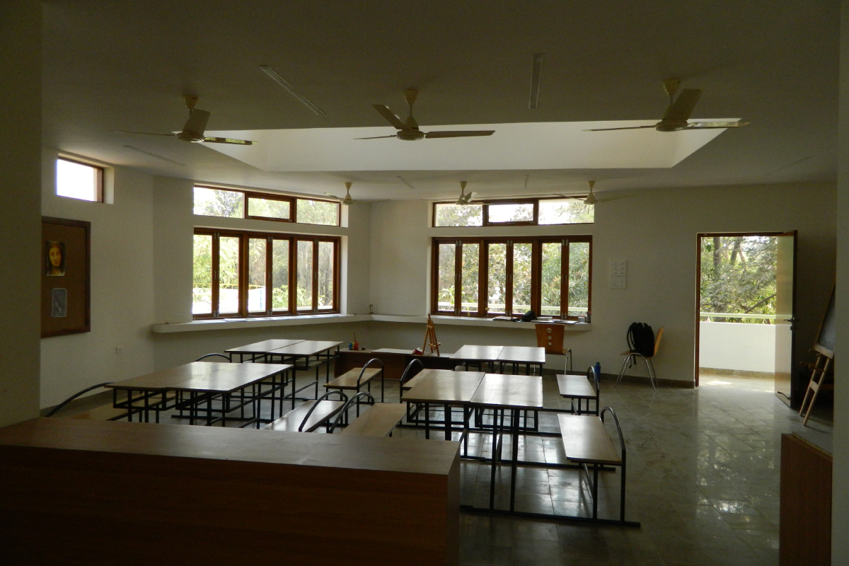 View of an empty, well-ventilated classroom with an open-air corridor in the background