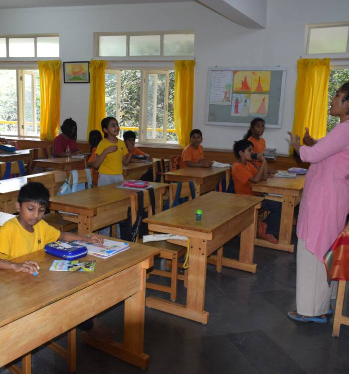 A teacher imparts a lesson to students in a lower school classroom.