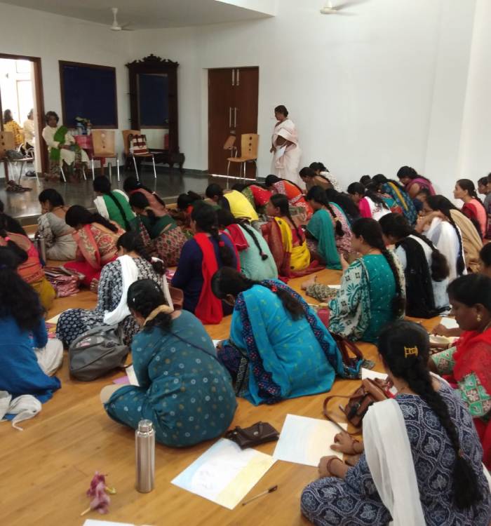 Several teachers sit on the floor taking notes during a tribal teacher training workshop at Sloka.