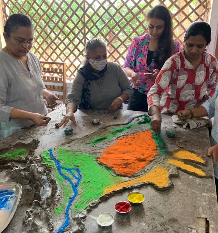 Several teachers sit on the floor taking notes during a tribal teacher training workshop at Sloka.