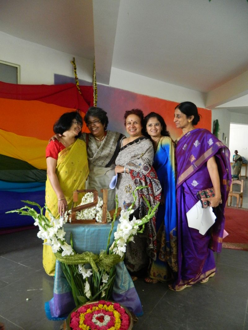 Five teachers smile and pose together next to a table decorated with floral arrangements.